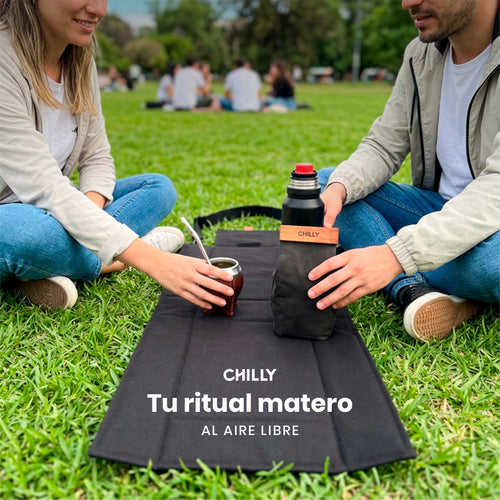 con bolso desplegado como mantel	Pareja compartiendo mate con bolso matero Chilly desplegado como mantel en el parque